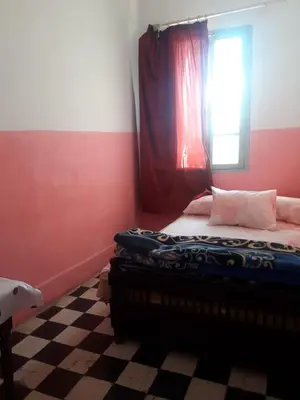 a bedroom with a bed with a window and a checkered floor at Hôtel Glacier in Fès
