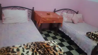 two beds in a room with a checkered floor at Hôtel Glacier in Fès