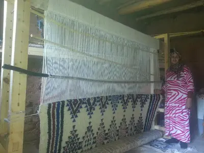 a woman standing next to a wall with a curtain at Gte Tawada - Haut-atlas - Chambre pour 2 Personnes in Ikhf nʼIghir