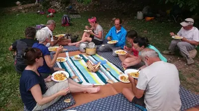a group of people sitting around a picnic table eating food at Gte Tawada - Haut-atlas - Chambre pour 2 Personnes in Ikhf nʼIghir
