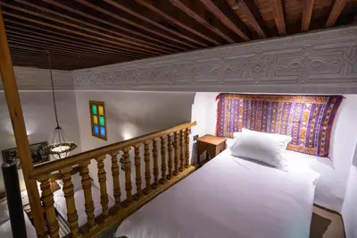 a bedroom with a white bed and a staircase at Riad Soultana in Fès