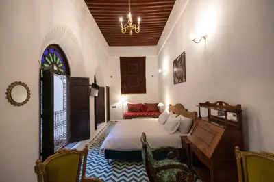 a bedroom with a bed and a desk and a window at Riad Soultana in Fès