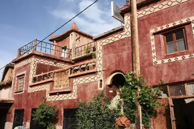 an old red building with a balcony on it at Gte Tawada - Valle Heureuse - Chambre pour 4 Personnes in Agouti
