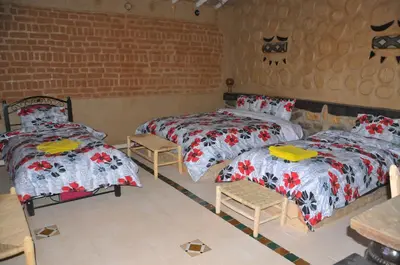 a bedroom with two beds and a brick wall at Maison Acacias in Erfoud