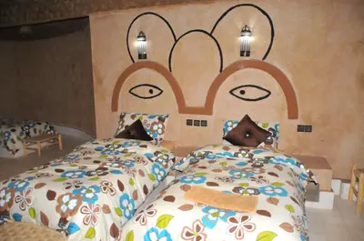 a bedroom with two beds with a face on the wall at Maison Acacias in Erfoud