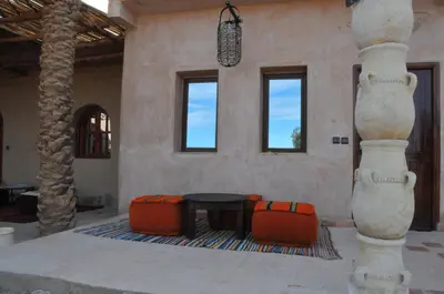 a room with a table and two ottomans at Maison Acacias in Erfoud