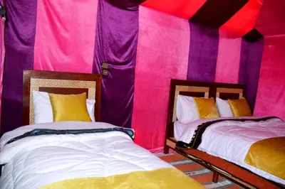 two beds in a room with pink and purple walls at Merzouga cheer camp in Merzouga