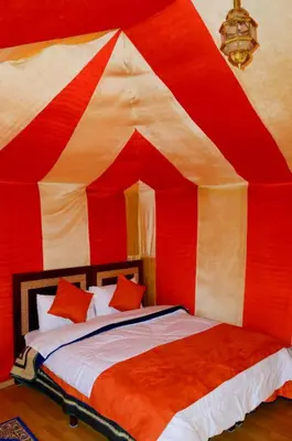 a bedroom with a red and white tent with a bed at Merzouga cheer camp in Merzouga