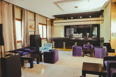 a waiting room with purple chairs and a barber shop at Hotel Perce Neige in Ifrane