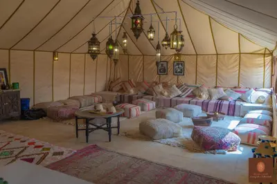 a room with couches and pillows in a tent at Beldi camp in Merzouga