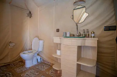 a bathroom with a toilet and a mirror at Beldi camp in Merzouga