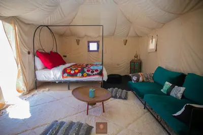a living room with a couch and a bed in a tent at Beldi camp in Merzouga