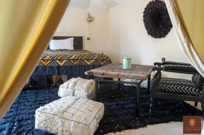 a bedroom with a bed and a table and chairs at Beldi camp in Merzouga