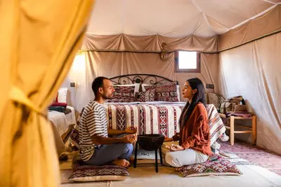 a man and woman sitting in a tent at Beldi camp in Merzouga