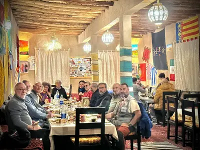 a group of people sitting at a table in a restaurant at Porte De Sahara Ouzina in Ouzina