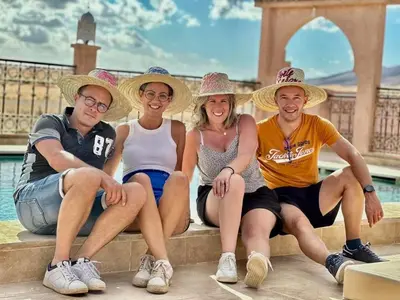 a group of people sitting on a ledge with hats at Porte De Sahara Ouzina in Ouzina
