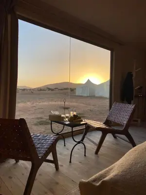a living room with a table and a view of the desert at THE SANDY TENTS in Merzouga