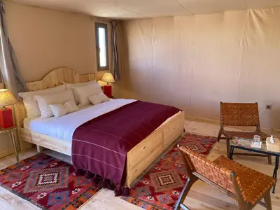 a bedroom with a bed and a chair and a table at THE SANDY TENTS in Merzouga