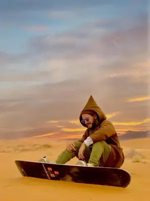 a man sitting on a snowboard in the desert at THE SANDY TENTS in Merzouga