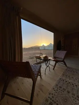 a living room with a view of the desert from a large window at THE SANDY TENTS in Merzouga