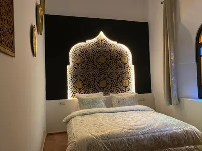 a bedroom with a bed with a moroccan head board at Riad Zyna in Meknès