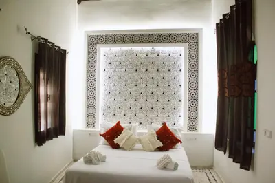 a bedroom with a bed with red and white pillows at Riad Zyna in Meknès