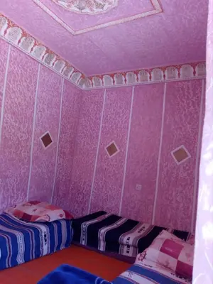 a bedroom with two beds and a pink wall at Gte Tawada - Haut-atlas - Chambre pour 4 Personnes in Agouti