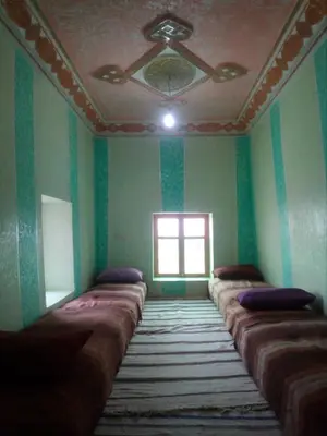 a room with a row of pillows on a wall at Gte Tawada - Haut-atlas - Chambre pour 4 Personnes in Agouti