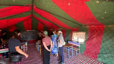 a group of people standing inside of a tent at Atta Desert Camp in El Gouera