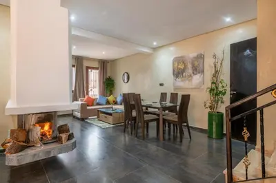 a living room with a fireplace and a dining room at Chalet Asmoun 2 in Imouzzer Kandar