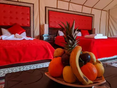 a bowl of fruit on a table in a room with two beds at NightStars Luxury Camp in Merzouga