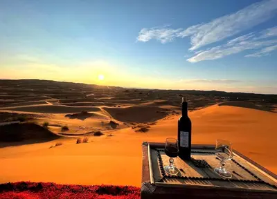 a bottle of wine sitting on a table in the desert at NightStars Luxury Camp in Merzouga