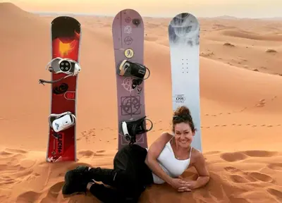 a woman sitting in the desert with two snowboards at NightStars Luxury Camp in Merzouga
