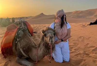 a woman standing next to a camel in the desert at NightStars Luxury Camp in Merzouga