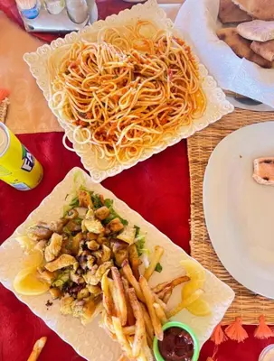 two plates of food with spaghetti and french fries on a table at NightStars Luxury Camp in Merzouga