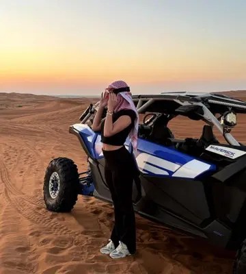 a woman standing in front of a car in the desert at NightStars Luxury Camp in Merzouga