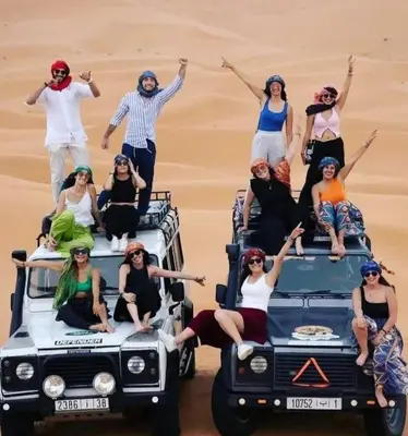 a group of people sitting on the roof of a jeep in the desert at Sahara Luxury Tented Camp in Merzouga