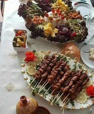 a table topped with plates of food on skewers at Sahara Luxury Tented Camp in Merzouga
