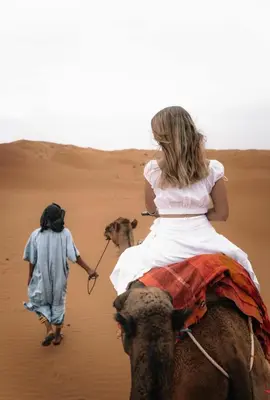 a woman riding on the back of a camel in the desert at Sahara Luxury Tented Camp in Merzouga