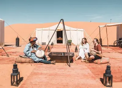 a group of people sitting in the desert at Sahara Luxury Tented Camp in Merzouga