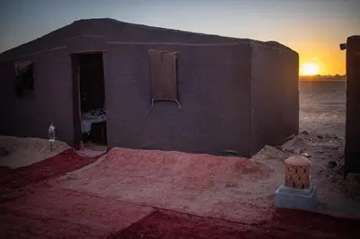 a building in the desert with the sunset in the background at Desert Luxury Camp in Mhamid