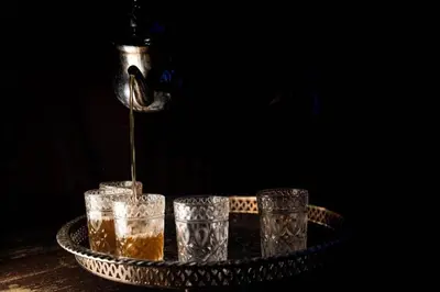 a drink is being poured into three glasses on a tray at Desert Luxury Camp in Mhamid