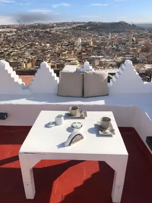 a white table on a roof with a view of a city at Riad Inaya Fez in Fès