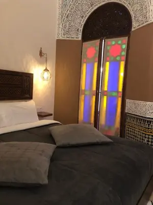 a bedroom with a bed and a stained glass window at Riad Inaya Fez in Fès