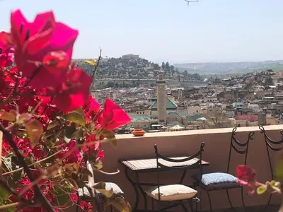 a balcony with two chairs and a view of a city at Riad Inaya Fez in Fès