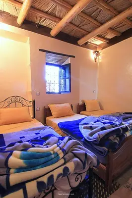 a bedroom with two beds and a window at Tigmi Tachddirt in Tacheddirt
