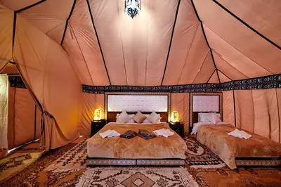 a bedroom with two beds in a tent at Golden Camel Desert Camp - Merzouga Luxury Camp in Merzouga