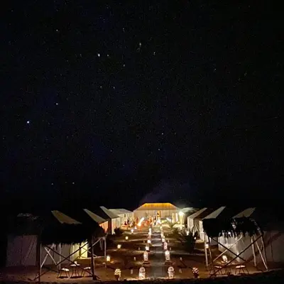 a group of tents with lights in the dark at Golden Camel Desert Camp - Merzouga Luxury Camp in Merzouga
