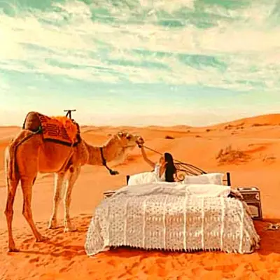 a woman and a camel in the desert at Golden Camel Desert Camp - Merzouga Luxury Camp in Merzouga