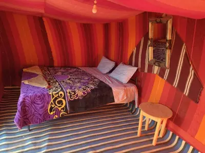 a bedroom with a bed in a striped room at Chegaga Nomad Camp in El Gouera